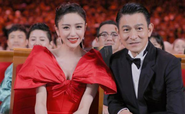 照片中,佟丽娅身穿红色礼服,坐在刘德华在身边,展露标准的露八颗牙齿