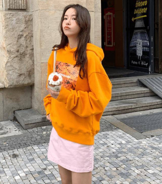 这件亮色系的橙色卫衣特别的显眼,短裙的搭配更是凸显了她的身材优势