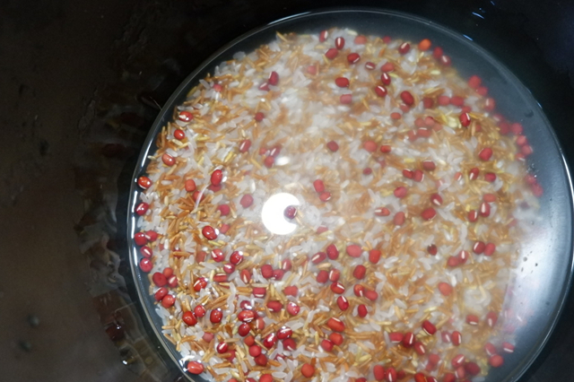 红豆以及淘洗干净的红米,大米放入电饭锅中,随后加入桂圆干和红皮花生