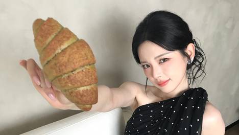 杨超越穿小黑裙俏皮灵动 拿面包拍照尽显娇憨可爱