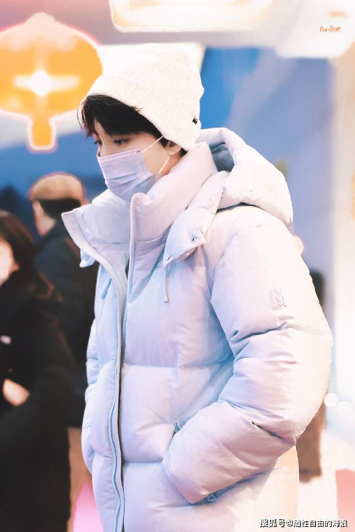 王俊凯穿着一件蓝色羽绒服,搭配一条白色西裤,整体造型少年感十足