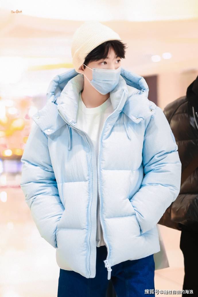 王俊凯穿着一件蓝色羽绒服,搭配一条白色西裤,整体造型少年感十足