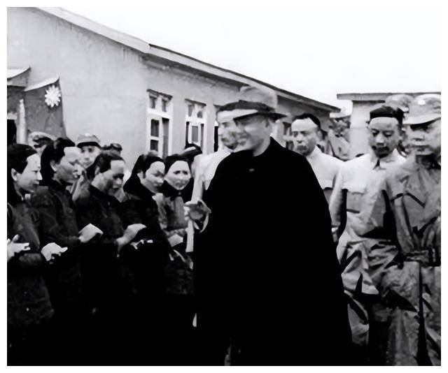 旧照片中,蒋介石头戴礼帽,手拄拐杖,身穿黑色风衣,脚蹬黑色长靴,在