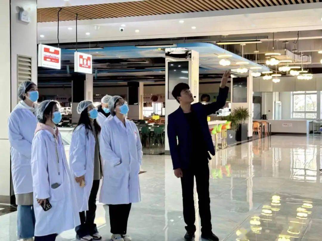 同学们身着白色工作服,有序参观餐具清洗消毒间,了解食堂碗筷消毒设备