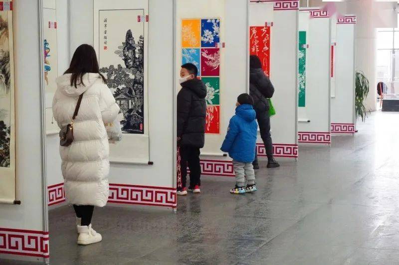 摄展览上,周老师给孩子们讲解了"龙马精神""喜从天降"等剪纸作品的