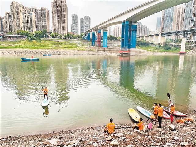杨兴安(左一)在江水中划桨板.