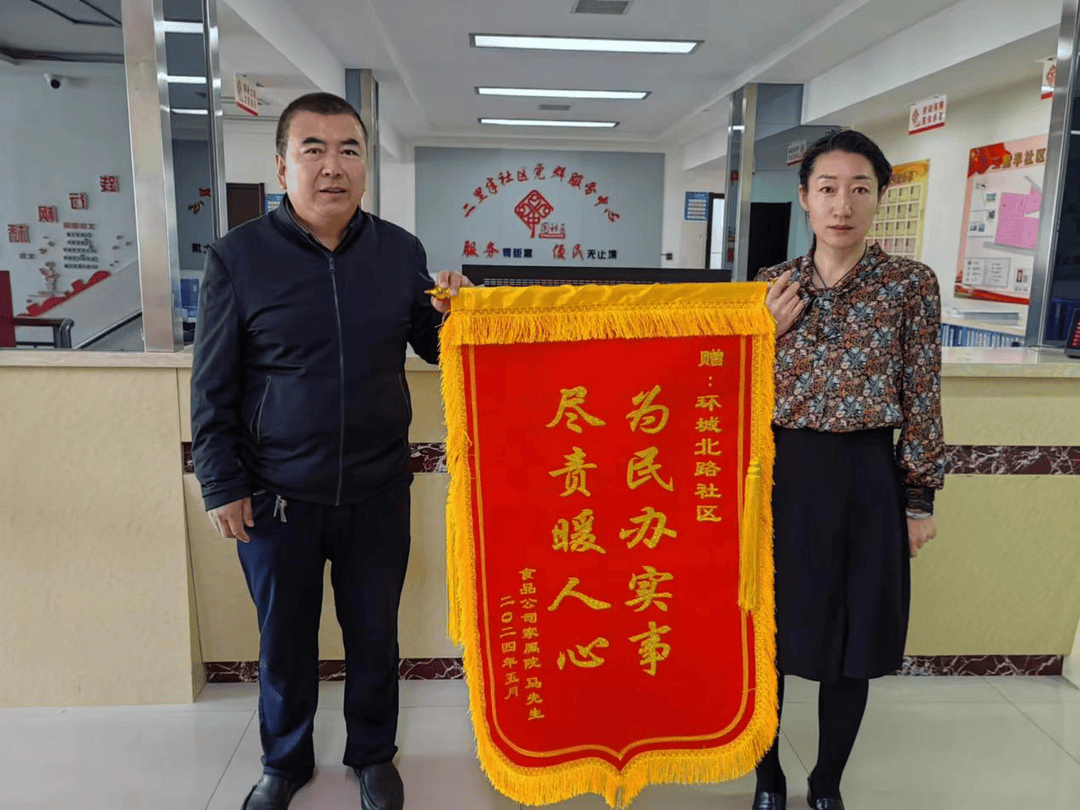 "居民马先生激动地将锦旗送到鼓楼街道环城北路社区工作人员的手中,并