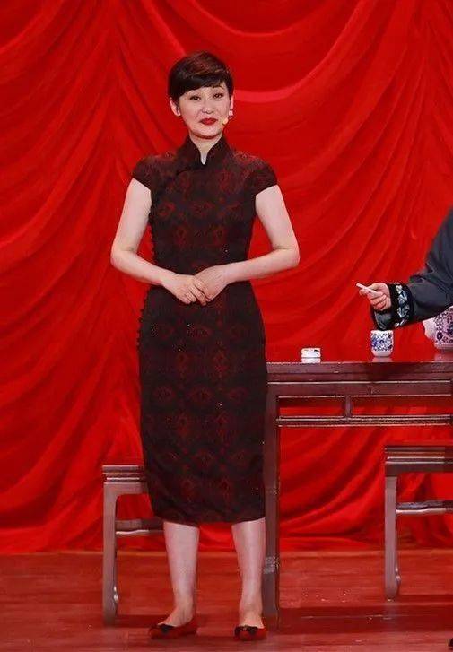 旗袍上精细的花纹设计增添了几分华丽感,她的双手自然下垂,面带微笑