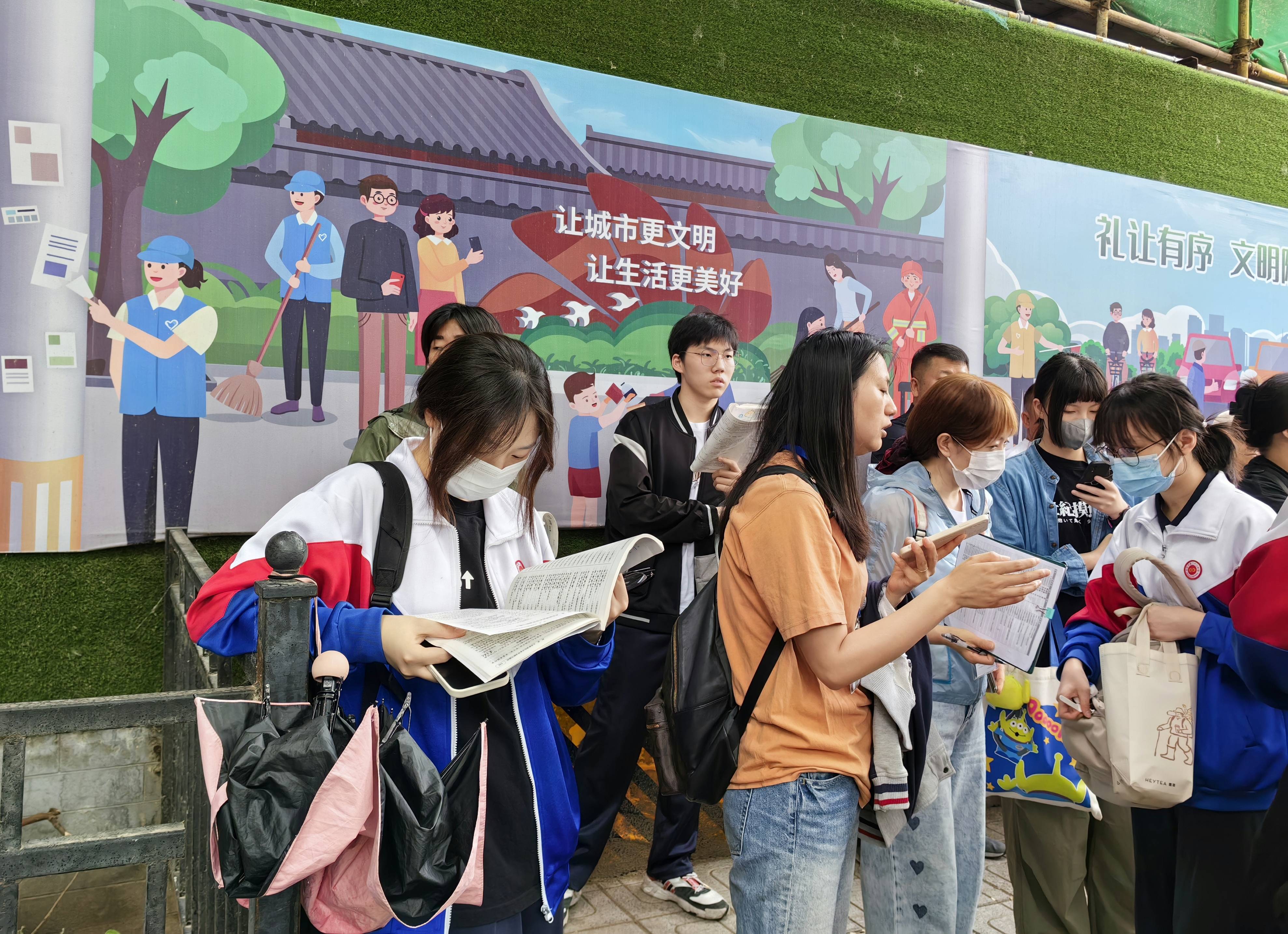 北京高考首日家长雨中送考,老师叮嘱考生"钥匙手机别带进考场"