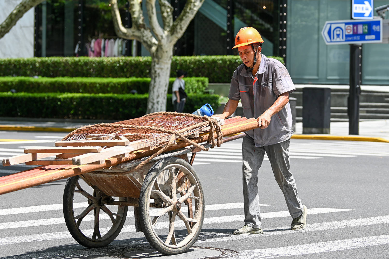 2024年7月30日,上海,烈日下,推板车的工人衣服都湿了